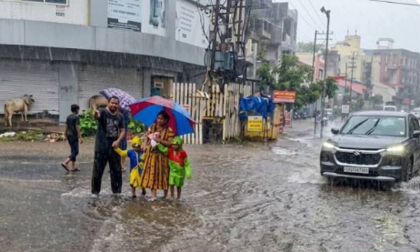 સુરતમાં વરસાદી માહોલ વચ્ચે રસ્તાઓ પર છત્રી લઈને જતા રાહદારીઓ.